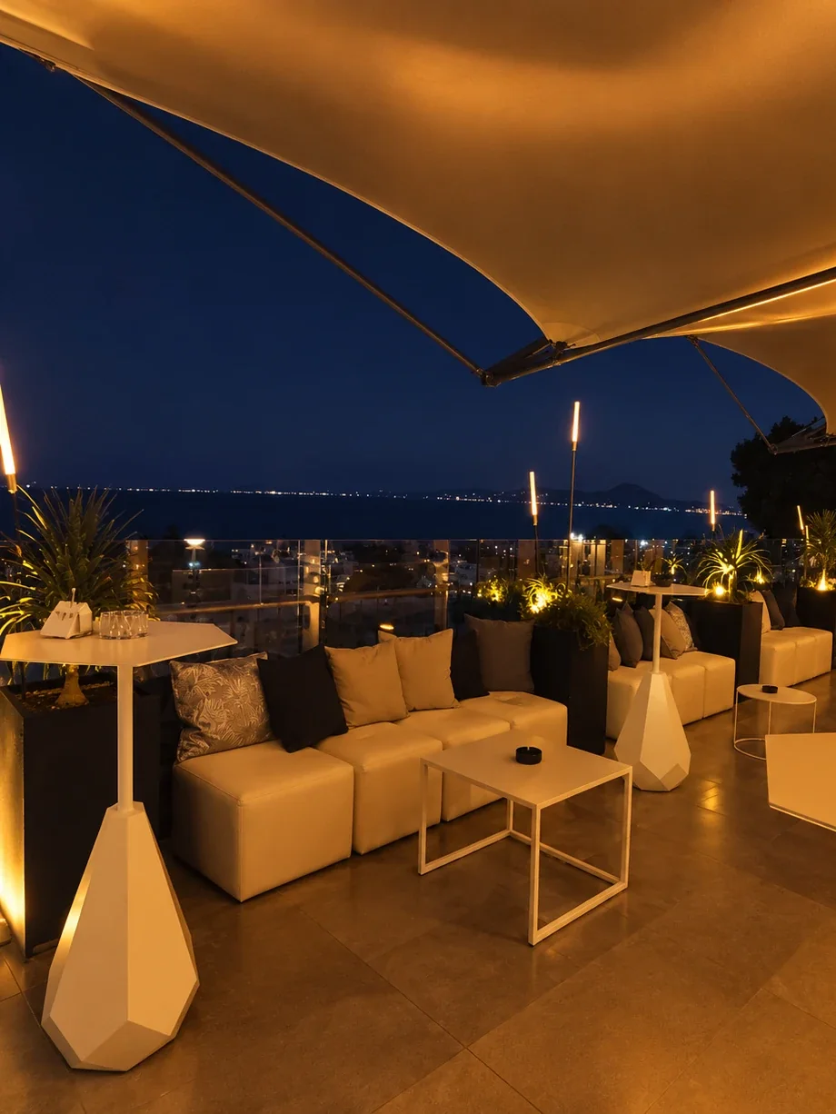 La Proue at blue hour, high tables and white banquettes beneath the shade sails, the bay of Carthage in the distance