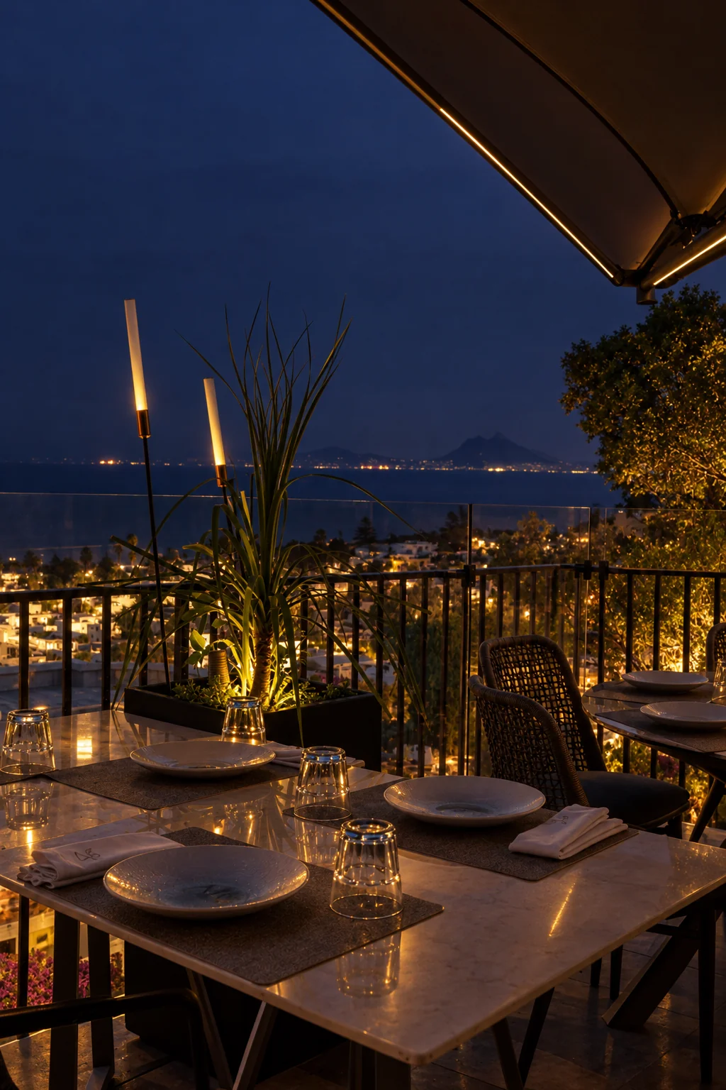 Tables dressées en terrasse à la nuit tombée, face à la baie de Carthage et au Boukornine